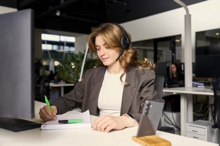 Tevreden vrouw met headset maakt aantekeningen