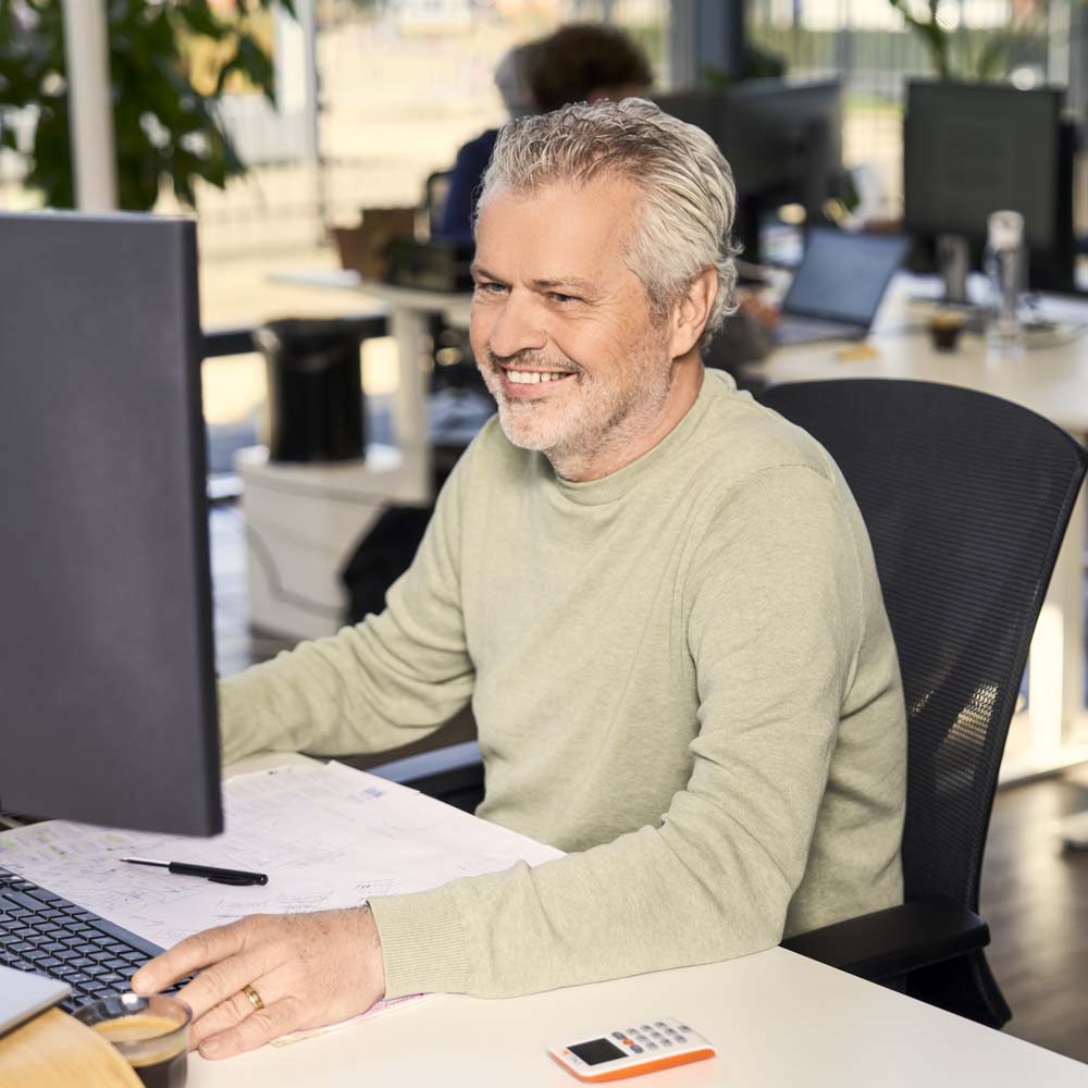 Vrolijke man voert administratieve taken uit op zijn pc