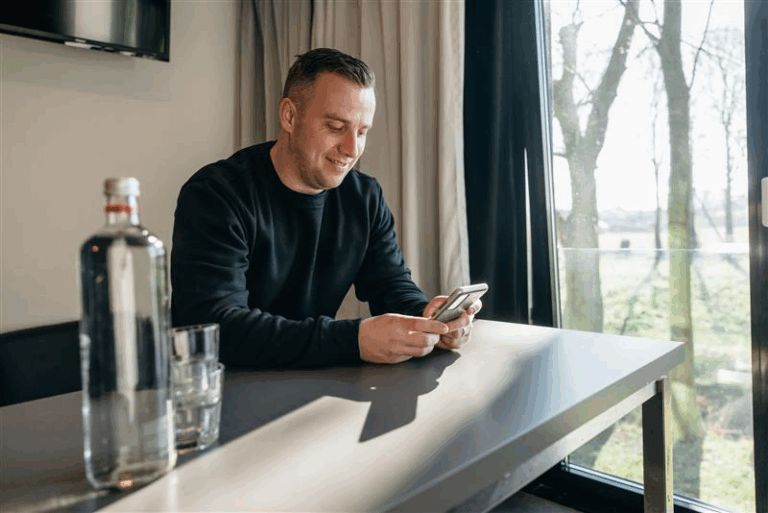 man-op-telefoon-in-huis